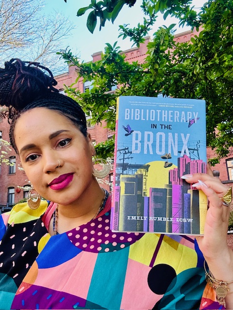 A photo of Emely joyfully holding up a copy of 'Bibliotherapy in the Bronx'